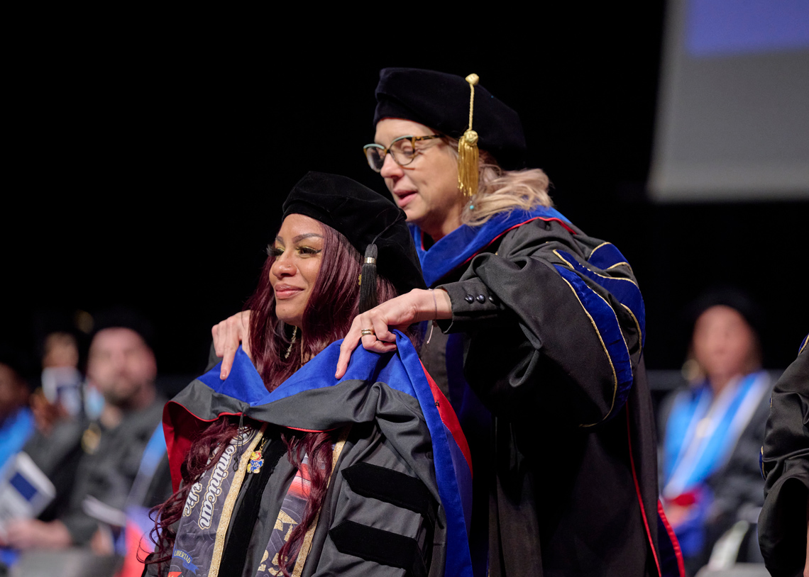A KU social work PhD candidate receives her doctoral hood during a graduation ceremony